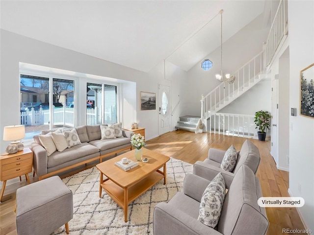 living room with a notable chandelier, high vaulted ceiling, and light hardwood / wood-style flooring