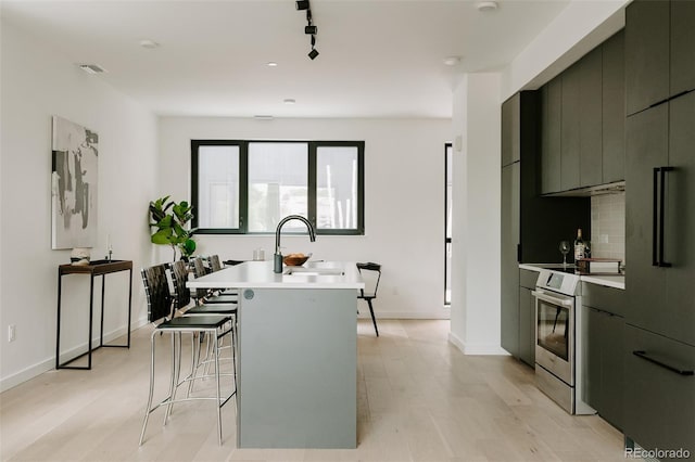 1601 Park Ave Unit 214, Denver, CO 80218 - kitchen with stainless steel range with electric cooktop, a sink, modern cabinets, a center island with sink, and light wood-style flooring