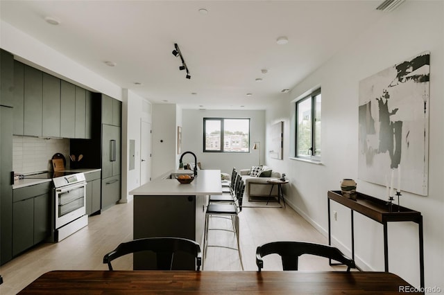 1601 Park Ave Unit 214, Denver, CO 80218 - kitchen featuring electric stove, a center island with sink, light countertops, and modern cabinets