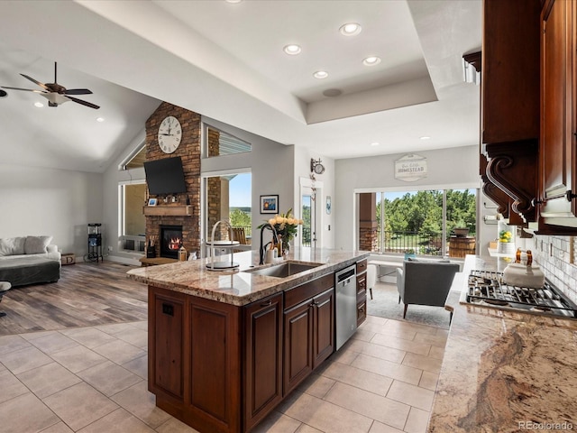 1505 Castlecombe Ln, Monument, CO 80132 - kitchen with open floor plan, a sink, stainless steel dishwasher, a ceiling fan, and a stone fireplace
