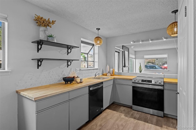 kitchen with a textured ceiling, wooden counters, dishwashing machine, and gray cabinets