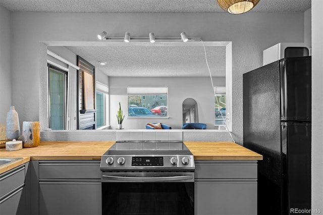 kitchen with wood counters, freestanding refrigerator, stainless steel electric stove, and gray cabinets