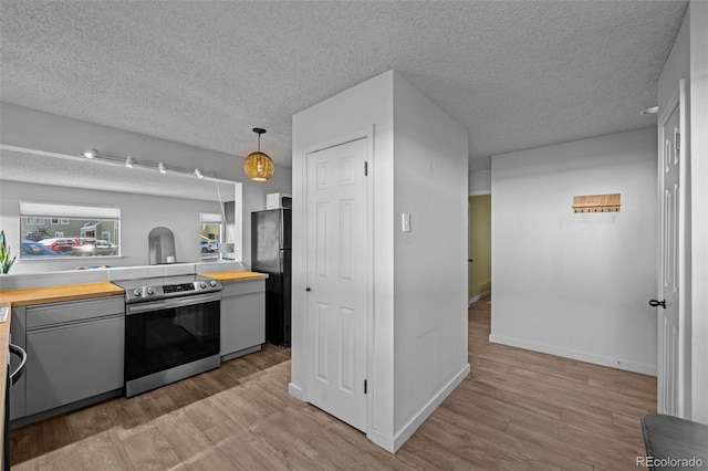 kitchen with wood counters, light wood-style floors, stainless steel electric stove, and gray cabinets