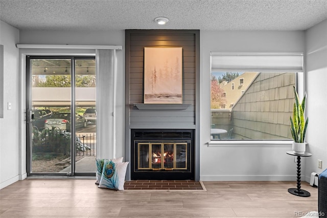 doorway featuring a textured ceiling, a baseboard heating unit, baseboards, wood finished floors, and a fireplace