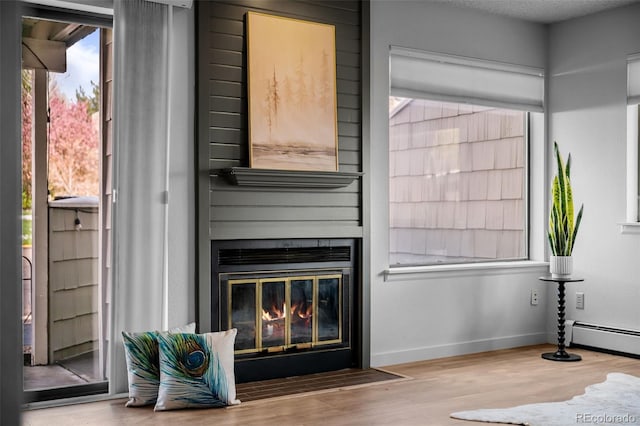 interior space featuring baseboards, a baseboard radiator, a fireplace, and wood finished floors