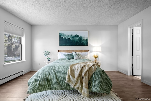 bedroom featuring a baseboard heating unit, a textured ceiling, and wood finished floors