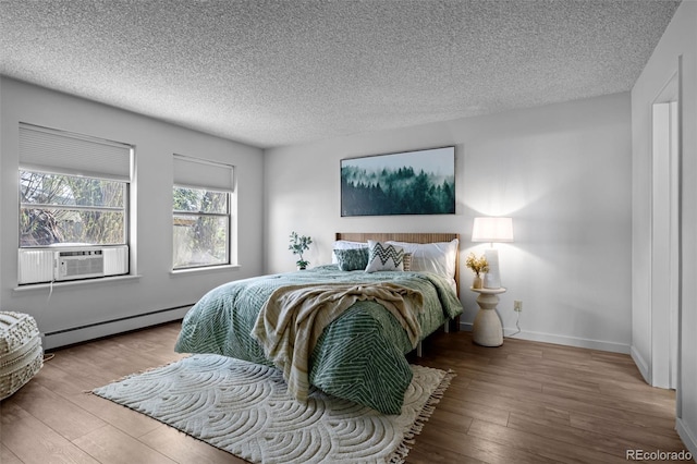 bedroom with cooling unit, a textured ceiling, wood finished floors, and a baseboard radiator