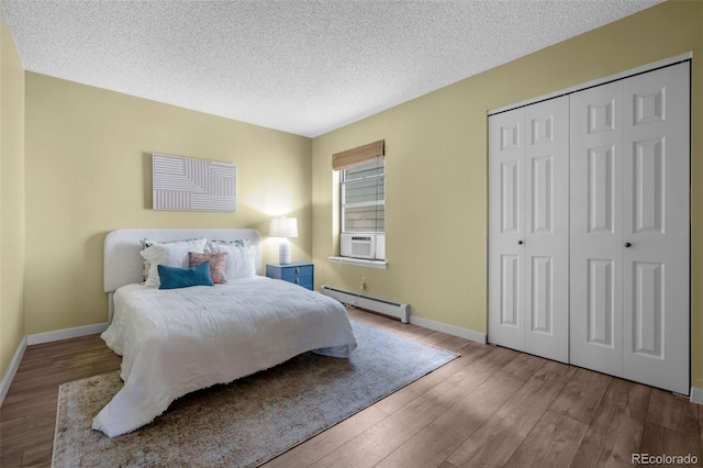 bedroom featuring a baseboard radiator, baseboards, a closet, and wood finished floors
