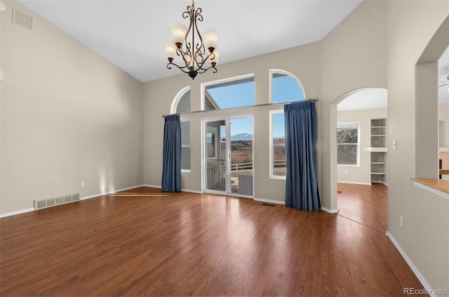 spare room with built in features, dark hardwood / wood-style flooring, and a chandelier