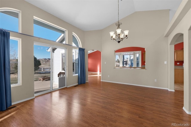 empty room with high vaulted ceiling, dark hardwood / wood-style floors, and an inviting chandelier