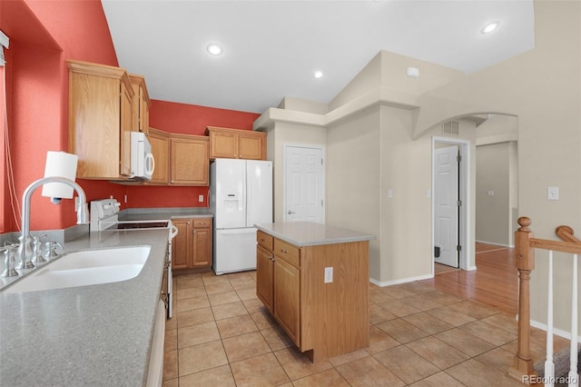 kitchen featuring white appliances, lofted ceiling, a kitchen island, sink, and light tile patterned floors