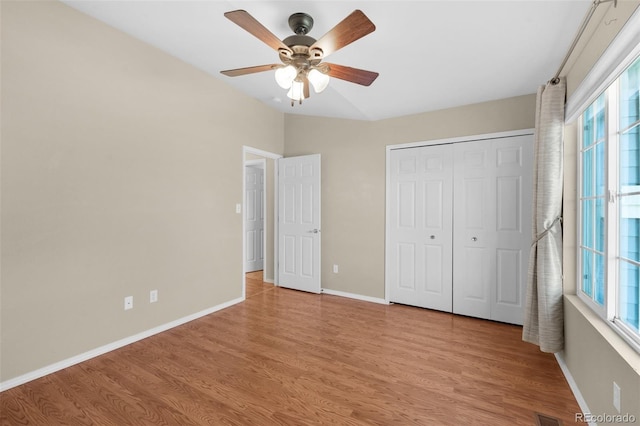 unfurnished bedroom featuring ceiling fan, a closet, multiple windows, and light hardwood / wood-style floors