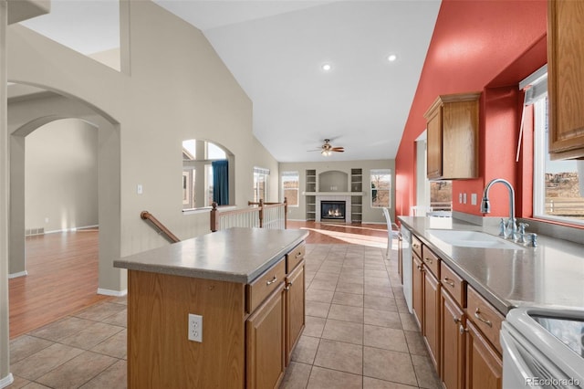 kitchen featuring a tile fireplace, a kitchen island, sink, light tile patterned floors, and built in shelves