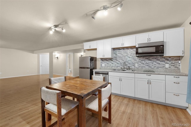 kitchen with appliances with stainless steel finishes, white cabinetry, tasteful backsplash, and sink