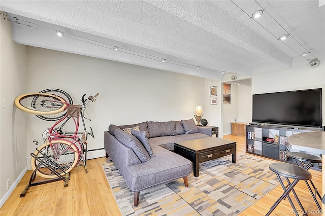 living area featuring rail lighting, a textured ceiling, baseboards, and wood finished floors