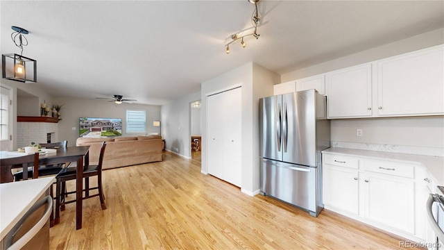 12201 N Holly Way, Brighton, CO 80602 - kitchen featuring freestanding refrigerator, ceiling fan, white cabinets, open floor plan, and light wood-style flooring
