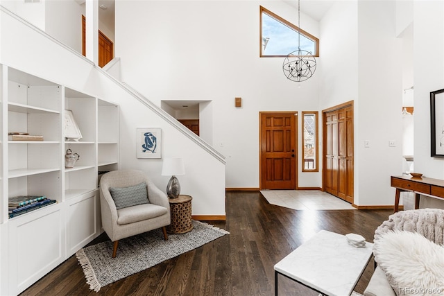 entryway with a high ceiling, an inviting chandelier, wood finished floors, and baseboards