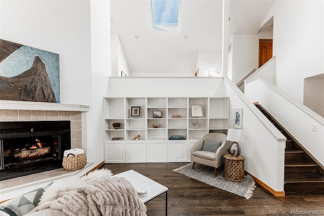 living room featuring stairs, a high ceiling, a tiled fireplace, and wood finished floors