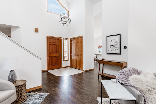 entrance foyer featuring baseboards, wood finished floors, a towering ceiling, and an inviting chandelier