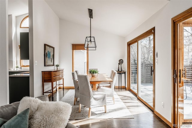 dining room featuring high vaulted ceiling, light wood-type flooring, and baseboards