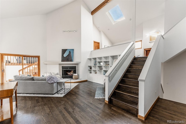 living room featuring stairs, high vaulted ceiling, wood finished floors, and a tile fireplace