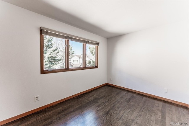 unfurnished room with dark wood-style flooring and baseboards