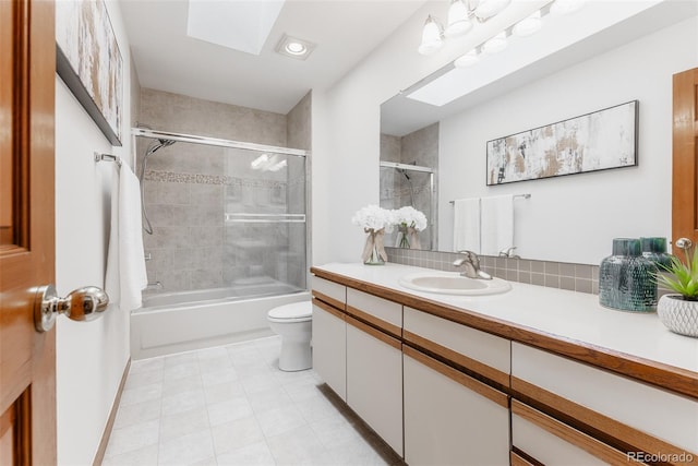 bathroom featuring toilet, a skylight, shower / bath combination with glass door, and vanity