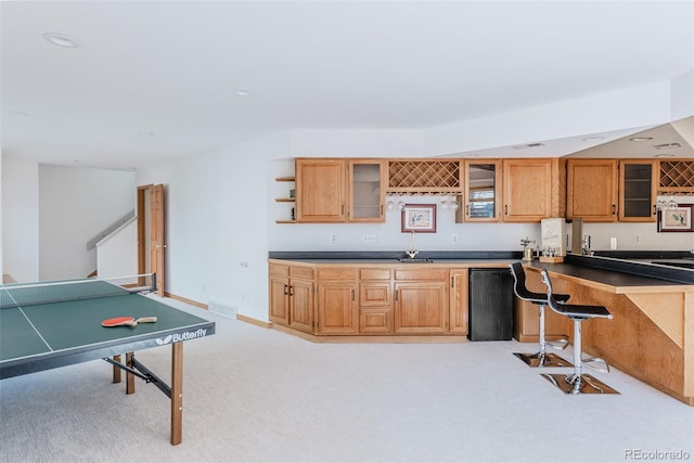 kitchen featuring light carpet, a sink, visible vents, dark countertops, and glass insert cabinets