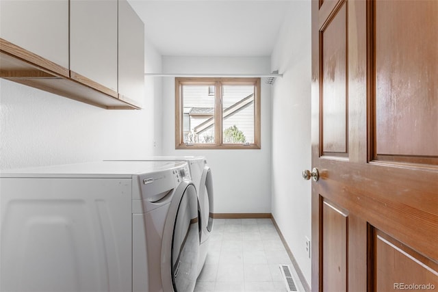 washroom featuring washing machine and dryer, cabinet space, visible vents, and baseboards