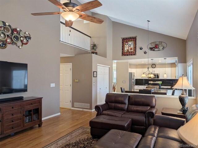 living room with ceiling fan, lofted ceiling, and light wood-type flooring