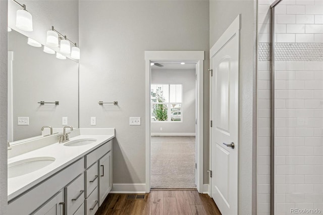 bathroom with tiled shower, wood-type flooring, and vanity