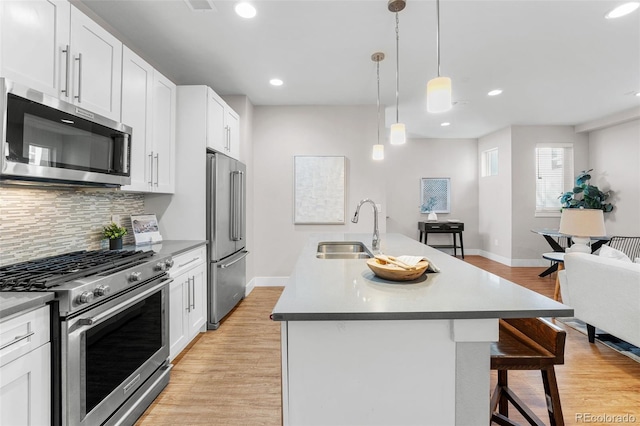 kitchen with sink, white cabinetry, hanging light fixtures, an island with sink, and stainless steel appliances