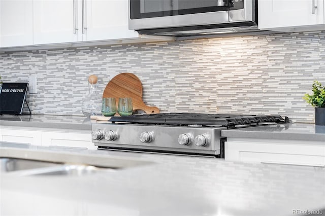 interior details with white cabinetry, range, and tasteful backsplash