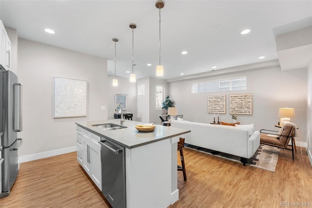 kitchen featuring stainless steel appliances, white cabinetry, sink, and a center island with sink