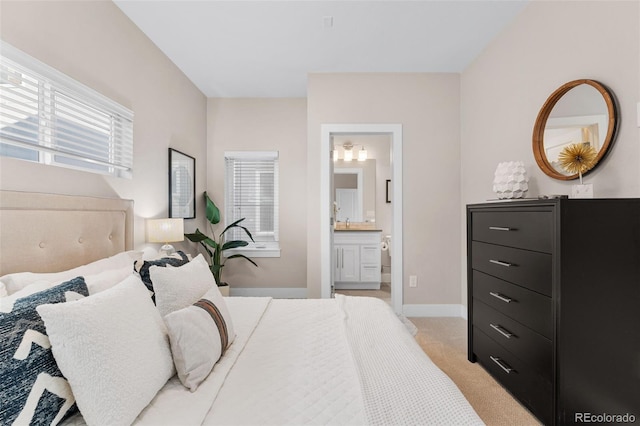 bedroom featuring ensuite bath and light colored carpet