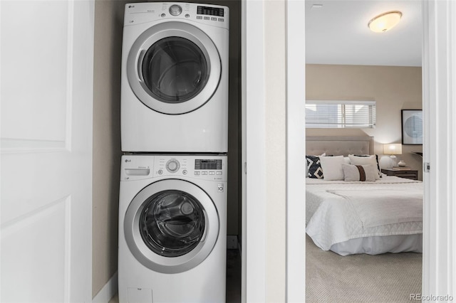 laundry area featuring stacked washer / dryer and carpet floors