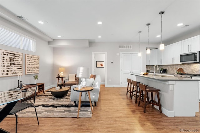 living room featuring recessed lighting, baseboards, visible vents, and light wood-style flooring
