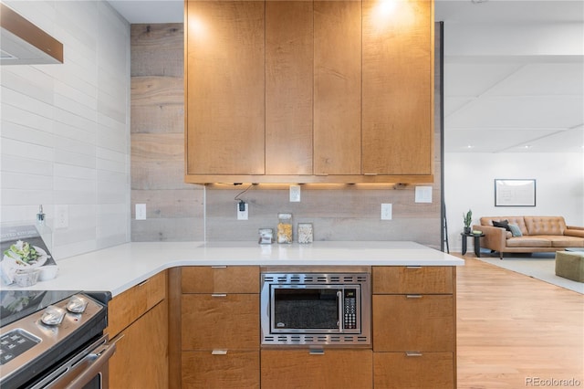 3035 E Maplewood Ave, Centennial, CO 80121 - kitchen with light countertops, decorative backsplash, stainless steel microwave, and wood finished floors