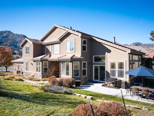 rear view of house with a mountain view, a yard, and a patio area