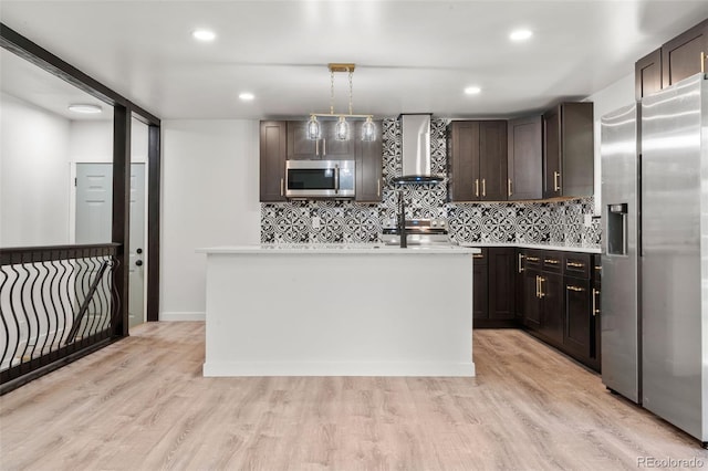 13010 W 6th Pl, Golden, CO 80401 - kitchen with appliances with stainless steel finishes, wall chimney exhaust hood, dark brown cabinets, light countertops, and a kitchen island