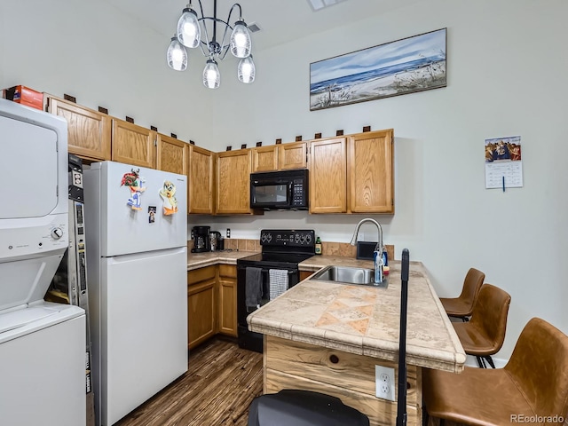 962 S Dearborn Way Unit 19, Aurora, CO 80012 - kitchen with stacked washer and clothes dryer, a peninsula, a sink, dark wood-type flooring, and black appliances