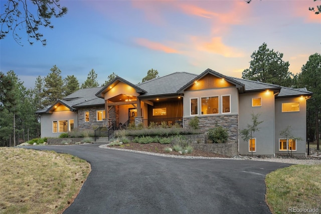 view of front of property with aphalt driveway, stone siding, and a tile roof