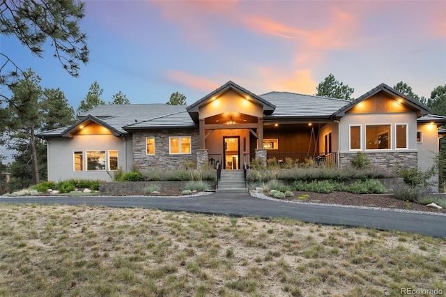 view of front of property featuring stone siding, stucco siding, and a tile roof