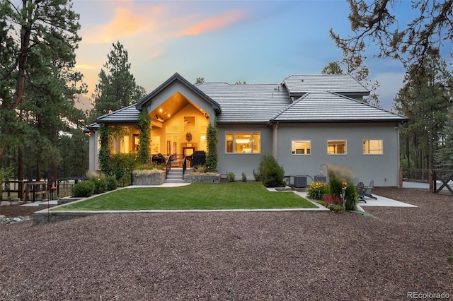 back house at dusk featuring a yard and cooling unit