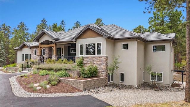 view of front facade with a tile roof, stone siding, and stucco siding