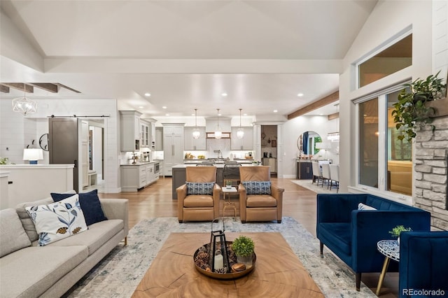 living area featuring recessed lighting, a barn door, light wood-style floors, and vaulted ceiling with beams