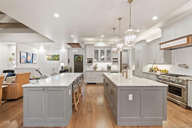 kitchen featuring stainless steel stove, open floor plan, gray cabinets, and a spacious island