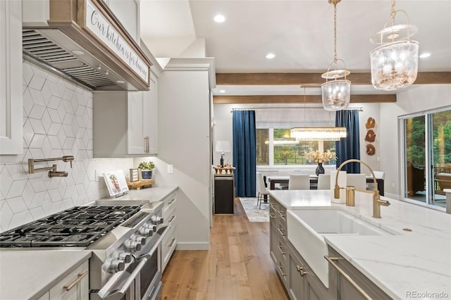 kitchen featuring double oven range, beam ceiling, light wood-style flooring, custom exhaust hood, and a sink