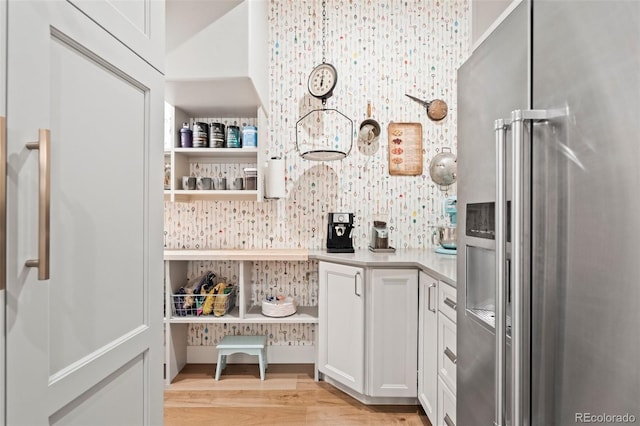 bar with high end refrigerator, light wood-type flooring, white cabinets, and decorative backsplash