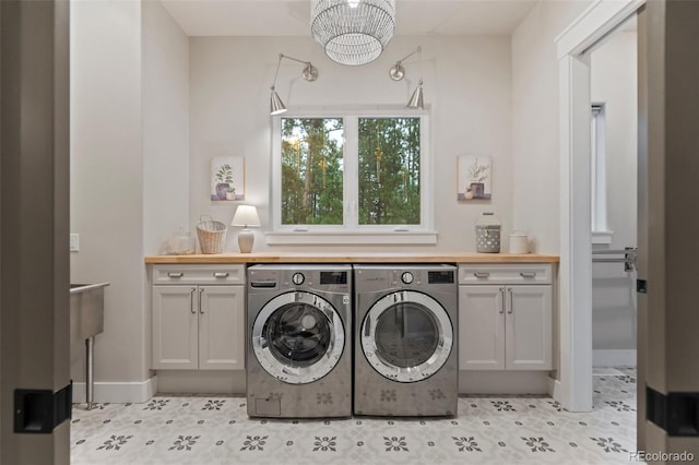 laundry room with a notable chandelier, washing machine and dryer, cabinet space, and baseboards